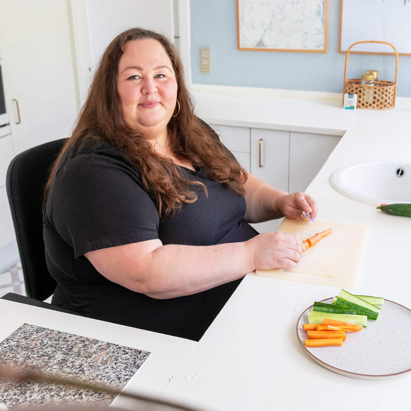 Overweight woman using the VELA kitchen chair for cooking vegetables
